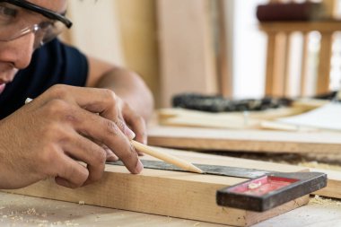 Marangoz atölyede ahşap işçiliği yapıyor. İnşaat malzemesi ya da ahşap mobilya üretiyor. Genç Asyalı marangoz zanaat için profesyonel araçlar kullanır. DIY üreticisi ve marangozluk konsepti.