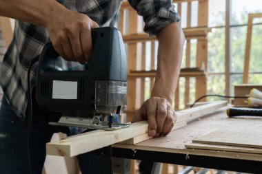 Marangoz atölyede ahşap işçiliği yapıyor. İnşaat malzemesi ya da ahşap mobilya üretiyor. Genç Asyalı marangoz zanaat için profesyonel araçlar kullanır. DIY üreticisi ve marangozluk konsepti.