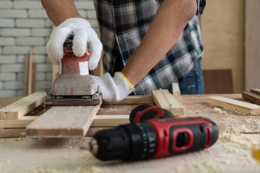 Marangoz atölyede ahşap işçiliği yapıyor. İnşaat malzemesi ya da ahşap mobilya üretiyor. Genç Asyalı marangoz zanaat için profesyonel araçlar kullanır. DIY üreticisi ve marangozluk konsepti.