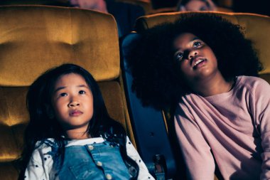 Üç çocuk eğleniyor ve sinemada film izlemekten zevk alıyor.
