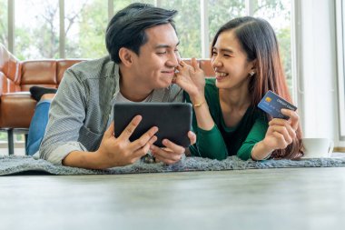 Genç çift evdeki internet sitesinden online alışveriş için kredi kartını kullanıyor. Kredi kartındaki numara sahte. Kredi kartında kişisel bilgi yok. Çevrimiçi iş alışveriş kavramı.