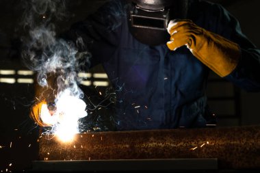 Fabrikada çelik kaynak makinesiyle çalışan metal kaynakçı güvenlik ekipmanı takıyor. El becerisi iş gücü kavramına göre metal imalatı ve inşaat bakım hizmeti.