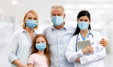 Doktor ve ailesi hastanede COVID-19 'dan korunmak için yüz maskesi takıyor. Halk sağlığı ve tıp konsepti.