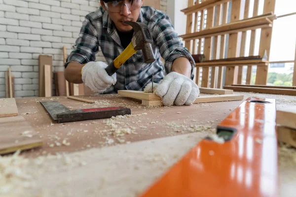 Carpenter working on wood craft at workshop to produce construction material or wooden furniture. The young Asian carpenter use professional tools for crafting. DIY maker and carpentry work concept.