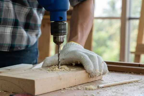 Marangoz atölyede ahşap işçiliği yapıyor. İnşaat malzemesi ya da ahşap mobilya üretiyor. Genç Asyalı marangoz zanaat için profesyonel araçlar kullanır. DIY üreticisi ve marangozluk konsepti.