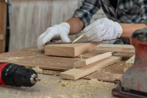 Marangoz atölyede ahşap işçiliği yapıyor. İnşaat malzemesi ya da ahşap mobilya üretiyor. Genç Asyalı marangoz zanaat için profesyonel araçlar kullanır. DIY üreticisi ve marangozluk konsepti.