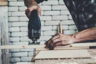 Marangoz atölyede ahşap işçiliği yapıyor. İnşaat malzemesi ya da ahşap mobilya üretiyor. Genç Asyalı marangoz zanaat için profesyonel araçlar kullanır. DIY üreticisi ve marangozluk konsepti.