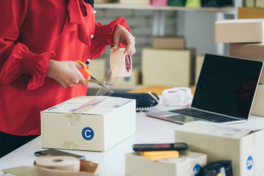 Çevrimiçi satıcı ev ofisinde çalışıyor ve teslimat kutusunu müşteriye paketliyor. İnternette e-ticaret yapan küçük işletme sahibi ya da girişimci.