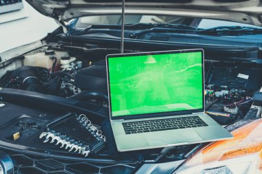 Motor kontrolü için arabanın kaputunda dizüstü bilgisayar var. Garaj tamiri konsepti.