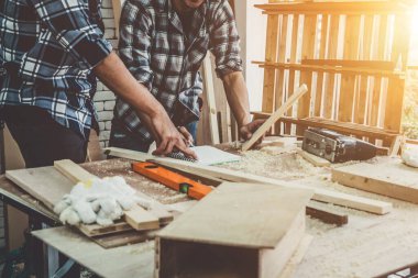 Marangoz atölyede ahşap işçiliği yapıyor. İnşaat malzemesi ya da ahşap mobilya üretiyor. Genç Asyalı marangoz zanaat için profesyonel araçlar kullanır. DIY üreticisi ve marangozluk konsepti.