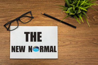 COVID 19 koronavirüsünden etkilenen yeni normal konsept, yaşam tarzımızı değiştirip, ofis masasında yazılan not defterinde anormalliğin yeni normal haline gelmesiyle ortaya çıkan yeni bir normal konsept. .