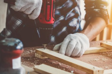 Marangoz atölyede ahşap işçiliği yapıyor. İnşaat malzemesi ya da ahşap mobilya üretiyor. Genç Asyalı marangoz zanaat için profesyonel araçlar kullanır. DIY üreticisi ve marangozluk konsepti.