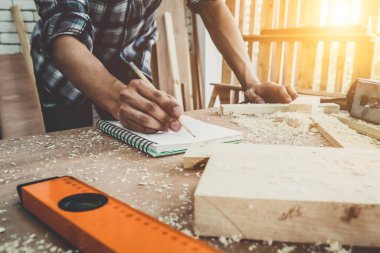 Marangoz atölyede ahşap işçiliği yapıyor. İnşaat malzemesi ya da ahşap mobilya üretiyor. Genç Asyalı marangoz zanaat için profesyonel araçlar kullanır. DIY üreticisi ve marangozluk konsepti.