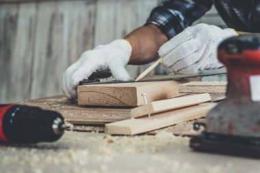 Marangoz atölyede ahşap işçiliği yapıyor. İnşaat malzemesi ya da ahşap mobilya üretiyor. Genç Asyalı marangoz zanaat için profesyonel araçlar kullanır. DIY üreticisi ve marangozluk konsepti.