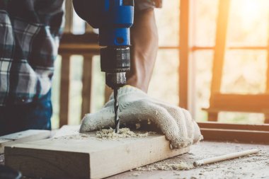 Marangoz atölyede ahşap işçiliği yapıyor. İnşaat malzemesi ya da ahşap mobilya üretiyor. Genç Asyalı marangoz zanaat için profesyonel araçlar kullanır. DIY üreticisi ve marangozluk konsepti.