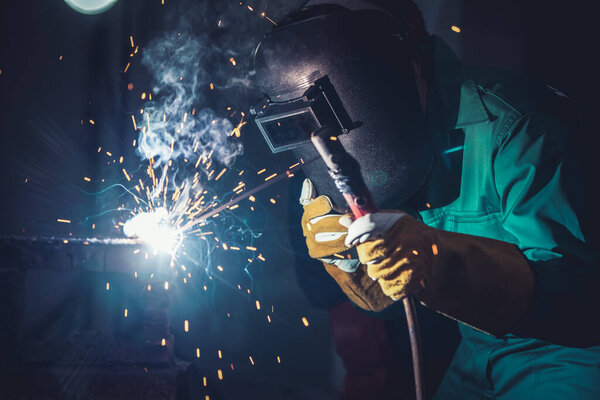 Metal welding steel works using electric arc welding machine to weld steel at factory. Metalwork manufacturing and construction maintenance service by manual skill labor concept.