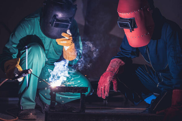 Metal welding steel works using electric arc welding machine to weld steel at factory. Metalwork manufacturing and construction maintenance service by manual skill labor concept.