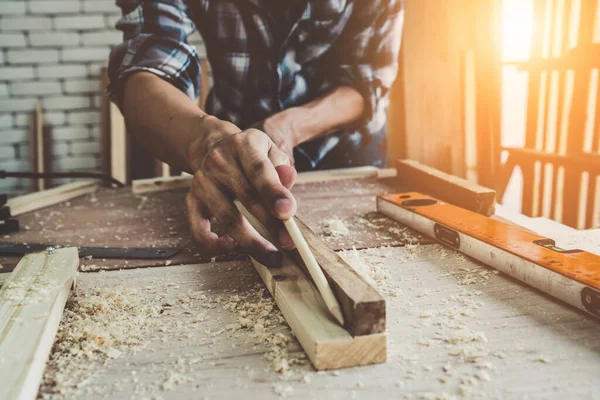 Carpenter working on wood craft at workshop to produce construction material or wooden furniture. The young Asian carpenter use professional tools for crafting. DIY maker and carpentry work concept.