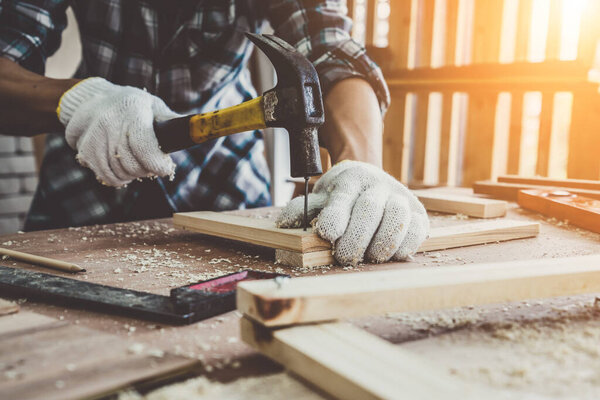 Carpenter working on wood craft at workshop to produce construction material or wooden furniture. The young Asian carpenter use professional tools for crafting. DIY maker and carpentry work concept.