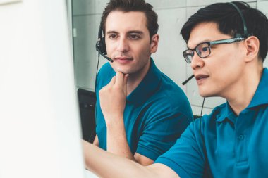 Ofiste çalışan kulaklık takan işadamları uzak müşteri ya da meslektaşlarını desteklemek için çalışıyorlar. Arama merkezi, tele pazarlama, müşteri destek acentesi telefon görüşmesinde hizmet sunar.