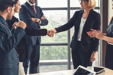 Şirket ofisinde iş adamlarının el sıkışması mali anlaşma konusunda profesyonel bir anlaşma gösteriyor.