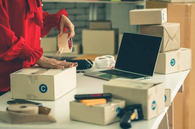 Çevrimiçi satıcı ev ofisinde çalışıyor ve teslimat kutusunu müşteriye paketliyor. İnternette e-ticaret yapan küçük işletme sahibi ya da girişimci.