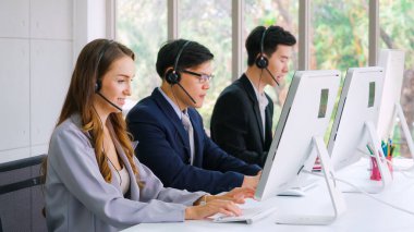 Ofiste çalışan kulaklık takan işadamları uzak müşteri ya da meslektaşlarını desteklemek için çalışıyorlar. Arama merkezi, tele pazarlama, müşteri destek acentesi telefon görüşmesinde hizmet sunar.