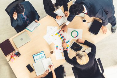 İş adamları grup toplantısı ofiste yukarıdan çekildi. İş kadınları, iş adamları ve ofis çalışanları, proje planlama belgeleriyle takım konferansında toplantı masasında çalışıyorlar. .
