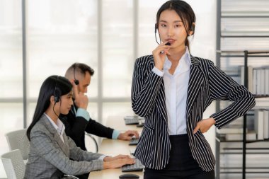 Ofiste çalışan kulaklık takan işadamları uzak müşteri ya da meslektaşlarını desteklemek için çalışıyorlar. Arama merkezi, tele pazarlama, müşteri destek acentesi telefon görüşmesinde hizmet sunar.