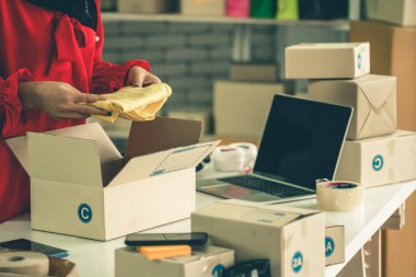 Çevrimiçi satıcı ev ofisinde çalışıyor ve teslimat kutusunu müşteriye paketliyor. İnternette e-ticaret yapan küçük işletme sahibi ya da girişimci.