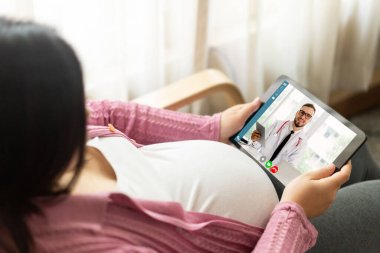 Hamile bir kadınla doğum öncesi bakım için internetten doktor teletıp hizmeti videosu. Canlı video çağrısı için internete bağlanan çevrimiçi mobil cihaz kullanarak evden uzak doktor sağlık danışmanı .