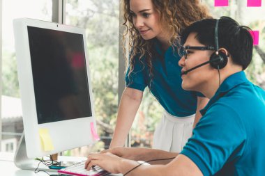 Ofiste çalışan kulaklık takan işadamları uzak müşteri ya da meslektaşlarını desteklemek için çalışıyorlar. Arama merkezi, tele pazarlama, müşteri destek acentesi telefon görüşmesinde hizmet sunar.