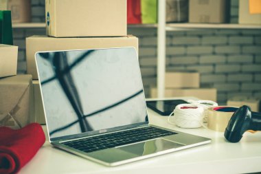 Nakliye kutusunun arka planında boş ekranı olan dizüstü bilgisayar. Çevrimiçi perakende satış mağazası, teslimat siparişi ve müşteri hizmetleri kavramı.