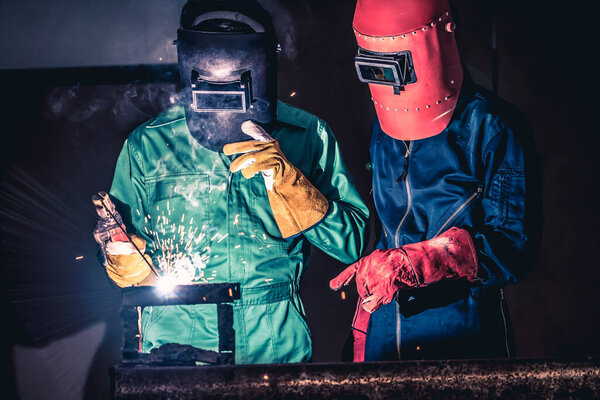 Metal welding steel works using electric arc welding machine to weld steel at factory. Metalwork manufacturing and construction maintenance service by manual skill labor concept.