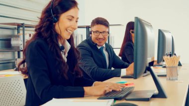 Ofiste çalışan kulaklık takan işadamları uzak müşteri ya da meslektaşlarını desteklemek için çalışıyorlar. Arama merkezi, tele pazarlama, müşteri destek acentesi telefon görüşmesinde hizmet sunar.