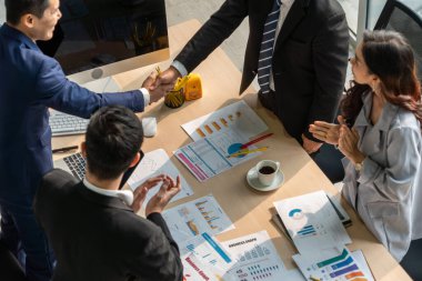 Grup iş adamları toplantı masasında el sıkışırken üst açıdan kendilerine güvenirler. Genç işadamı ve işkadını işçiler yatırım anlaşması imzaladılar.