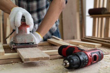 Marangoz atölyede ahşap işçiliği yapıyor. İnşaat malzemesi ya da ahşap mobilya üretiyor. Genç Asyalı marangoz zanaat için profesyonel araçlar kullanır. DIY üreticisi ve marangozluk konsepti.