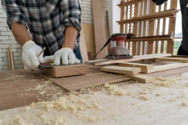 Marangoz atölyede ahşap işçiliği yapıyor. İnşaat malzemesi ya da ahşap mobilya üretiyor. Genç Asyalı marangoz zanaat için profesyonel araçlar kullanır. DIY üreticisi ve marangozluk konsepti.