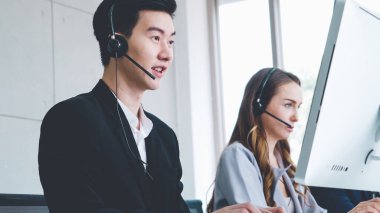 Ofiste çalışan kulaklık takan işadamları uzak müşteri ya da meslektaşlarını desteklemek için çalışıyorlar. Arama merkezi, tele pazarlama, müşteri destek acentesi telefon görüşmesinde hizmet sunar.