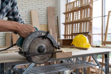 Marangoz atölyede ahşap işçiliği yapıyor. İnşaat malzemesi ya da ahşap mobilya üretiyor. Genç Asyalı marangoz zanaat için profesyonel araçlar kullanır. DIY üreticisi ve marangozluk konsepti.