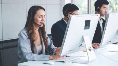 Ofiste çalışan kulaklık takan işadamları uzak müşteri ya da meslektaşlarını desteklemek için çalışıyorlar. Arama merkezi, tele pazarlama, müşteri destek acentesi telefon görüşmesinde hizmet sunar.