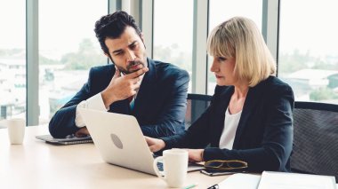 İki iş adamı toplantı odasında proje stratejisi hakkında konuşuyor. İş adamı, mali veri raporu hakkında sohbet ve tavsiyelerde bulunurken, modern işyerindeki iş arkadaşıyla proje planlamasını tartıştı.