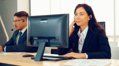 Ofiste çalışan kulaklık takan işadamları uzak müşteri ya da meslektaşlarını desteklemek için çalışıyorlar. Arama merkezi, tele pazarlama, müşteri destek acentesi telefon görüşmesinde hizmet sunar.
