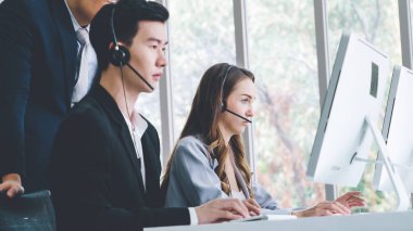 Ofiste çalışan kulaklık takan işadamları uzak müşteri ya da meslektaşlarını desteklemek için çalışıyorlar. Arama merkezi, tele pazarlama, müşteri destek acentesi telefon görüşmesinde hizmet sunar.