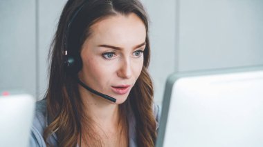 Ofiste çalışan kulaklık takan işadamları uzak müşteri ya da meslektaşlarını desteklemek için çalışıyorlar. Arama merkezi, tele pazarlama, müşteri destek acentesi telefon görüşmesinde hizmet sunar.