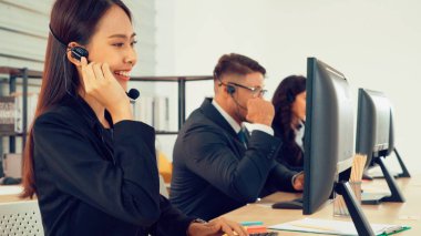 Ofiste çalışan kulaklık takan işadamları uzak müşteri ya da meslektaşlarını desteklemek için çalışıyorlar. Arama merkezi, tele pazarlama, müşteri destek acentesi telefon görüşmesinde hizmet sunar.