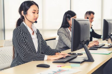 Ofiste çalışan kulaklık takan işadamları uzak müşteri ya da meslektaşlarını desteklemek için çalışıyorlar. Arama merkezi, tele pazarlama, müşteri destek acentesi telefon görüşmesinde hizmet sunar.