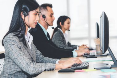 Ofiste çalışan kulaklık takan işadamları uzak müşteri ya da meslektaşlarını desteklemek için çalışıyorlar. Arama merkezi, tele pazarlama, müşteri destek acentesi telefon görüşmesinde hizmet sunar.