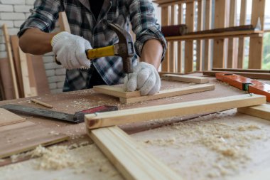 Marangoz atölyede ahşap işçiliği yapıyor. İnşaat malzemesi ya da ahşap mobilya üretiyor. Genç Asyalı marangoz zanaat için profesyonel araçlar kullanır. DIY üreticisi ve marangozluk konsepti.