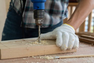 Marangoz atölyede ahşap işçiliği yapıyor. İnşaat malzemesi ya da ahşap mobilya üretiyor. Genç Asyalı marangoz zanaat için profesyonel araçlar kullanır. DIY üreticisi ve marangozluk konsepti.